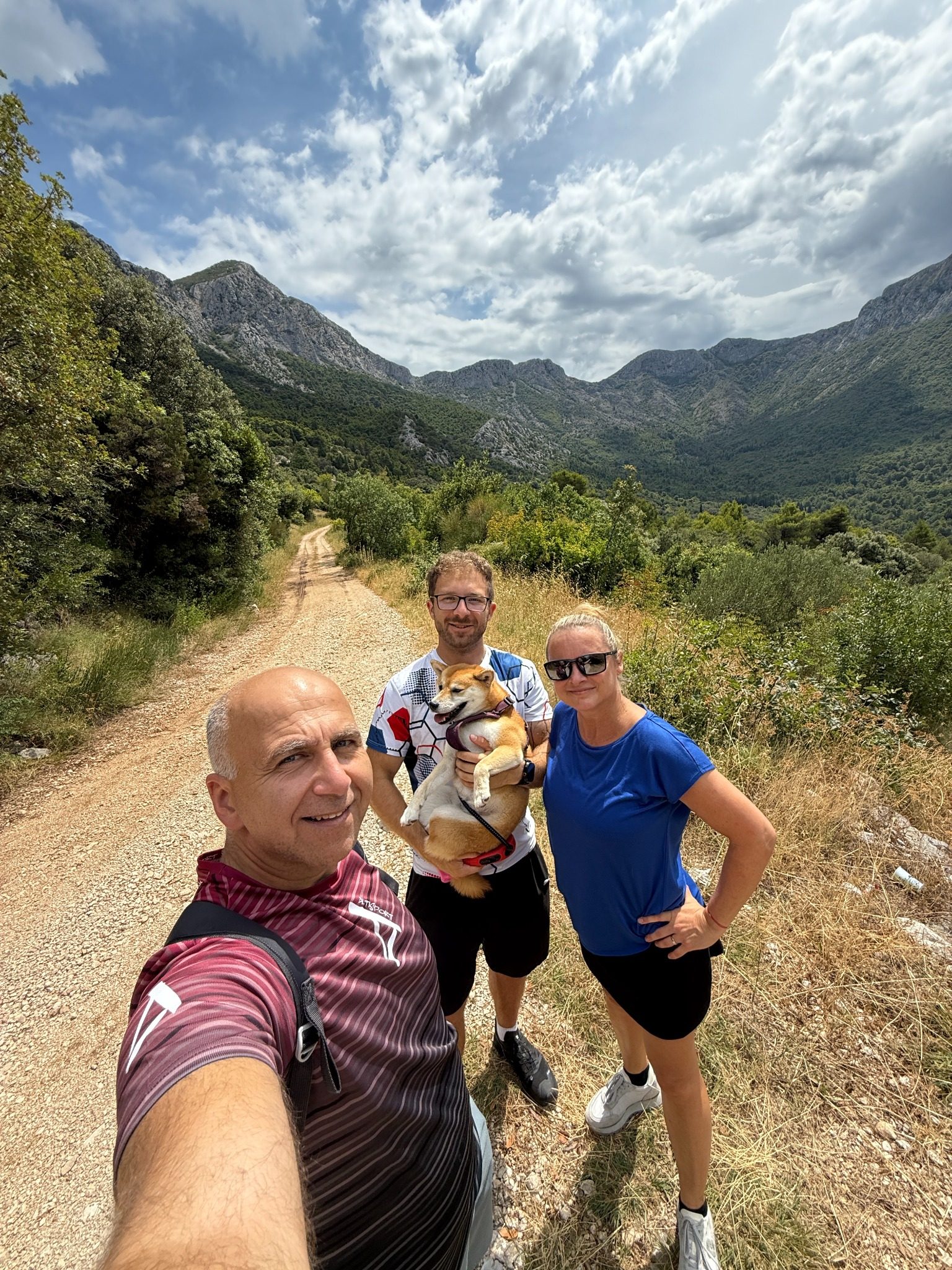 Trei persoane cu un câine într-o excursie la munte