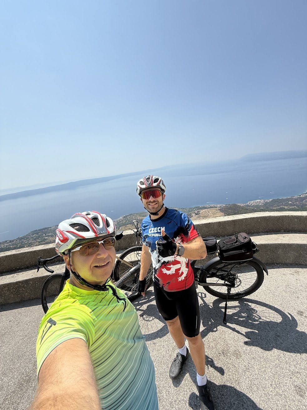 Doi bicicliști cu biciclete la un punct de belvedere deasupra coastei