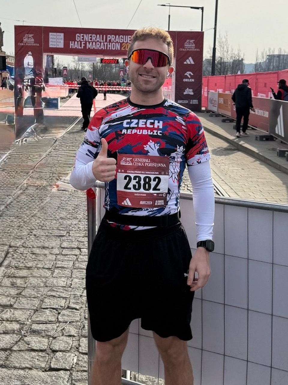 Un alergător cu număr de start și ochelari de sport în fața zonei de sosire a cursei