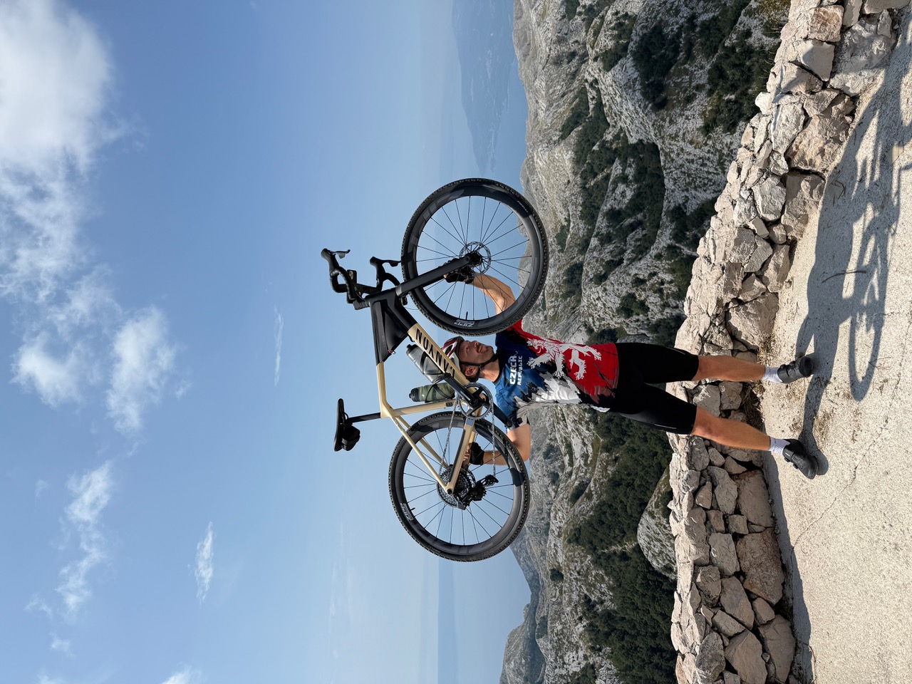 Un biciclist oprește o bicicletă la un punct de belvedere asupra unui peisaj montan